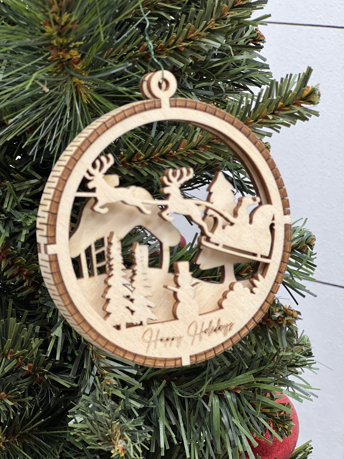 This is a round wooden Christmas ornament with a winter scene with a living hinge. It’s Santa on his midnight run.