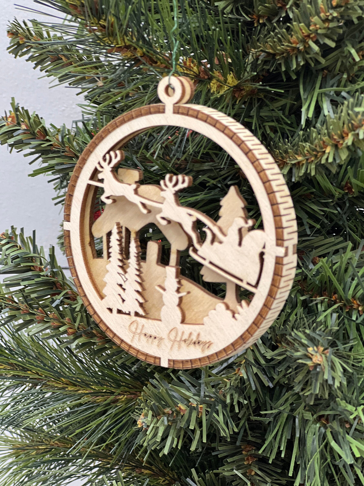 This is a round wooden Christmas ornament with a winter scene with a living hinge. It’s Santa on his midnight run.