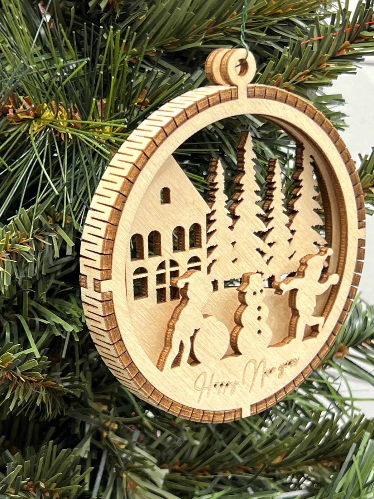 This is a round wooden Christmas ornament with a winter scene with a living hinge. It shows the kids having fun playing in the snow.