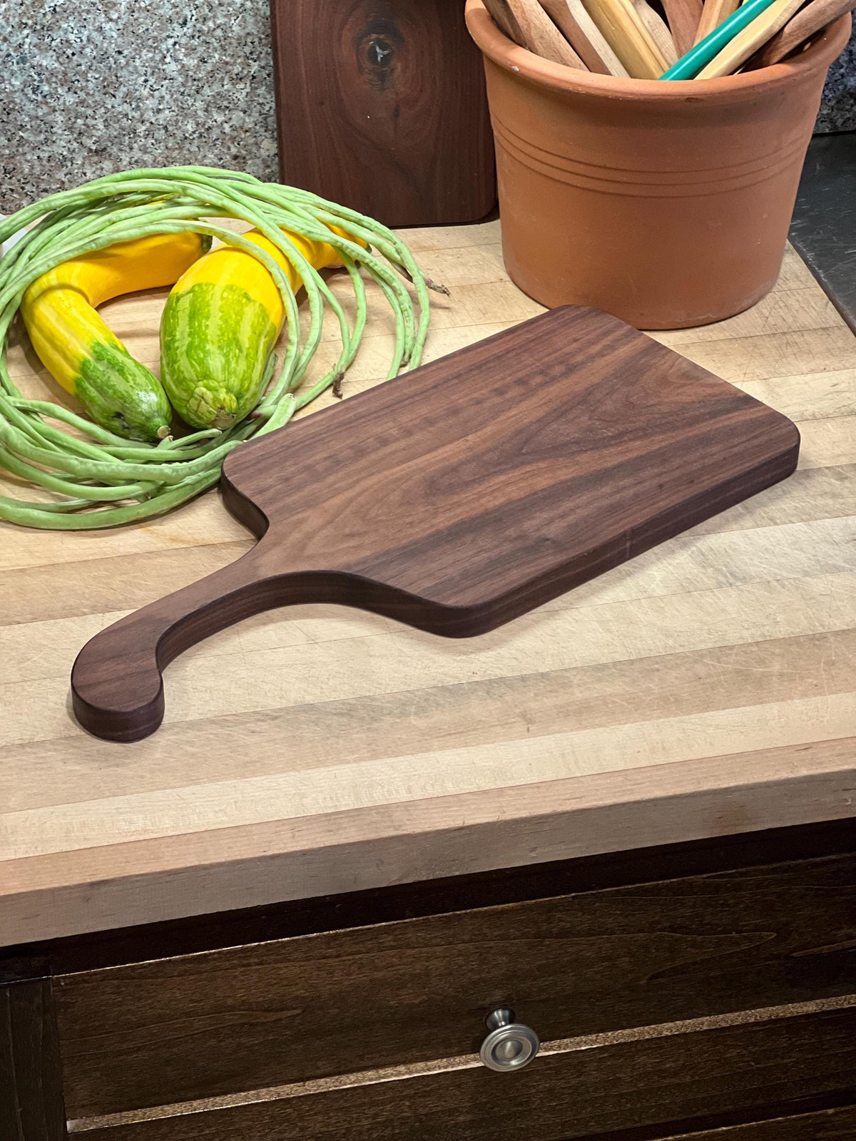 This is a handmade, solid wood walnut , custom design handle cutting board. The dimensions of this board are 17”x7 1/2”x3/4”.